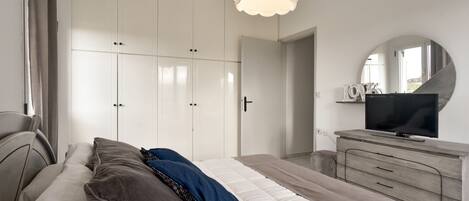 Un dormitorio con cama, cómoda, televisor y armario.