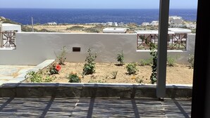A terrace with a view of the sea, featuring a pergola structure and a stone wall.