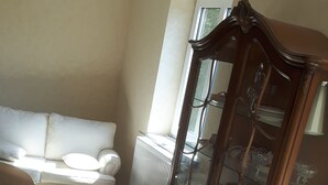 Ein Wohnzimmer mit einem weißen Sofa, einer Holzkommode und einem Fenster.