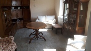 Ein Zimmer mit einem runden Holztisch, einer Couch, einer Bank und Holzsäcken.
