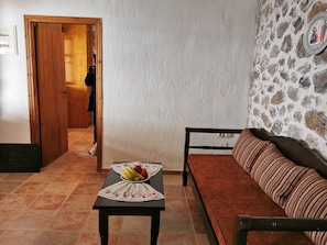 Une pièce avec une porte en bois, un mur en pierre, un canapé et une table sur laquelle se trouvent des fruits.