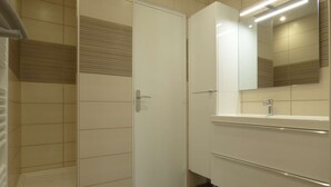 A modern bathroom with a white vanity, a mirror, and a door.