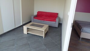 A small living area with a grey sofa, a red throw blanket, and a wooden coffee table.