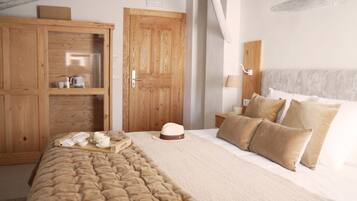 A bedroom with a large wooden wardrobe, a bed with a beige quilt, and a nightstand with a lamp.