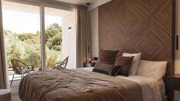 Une chambre avec un grand lit, une vue sur la verdure et un motif décoratif en bois sur un des murs.