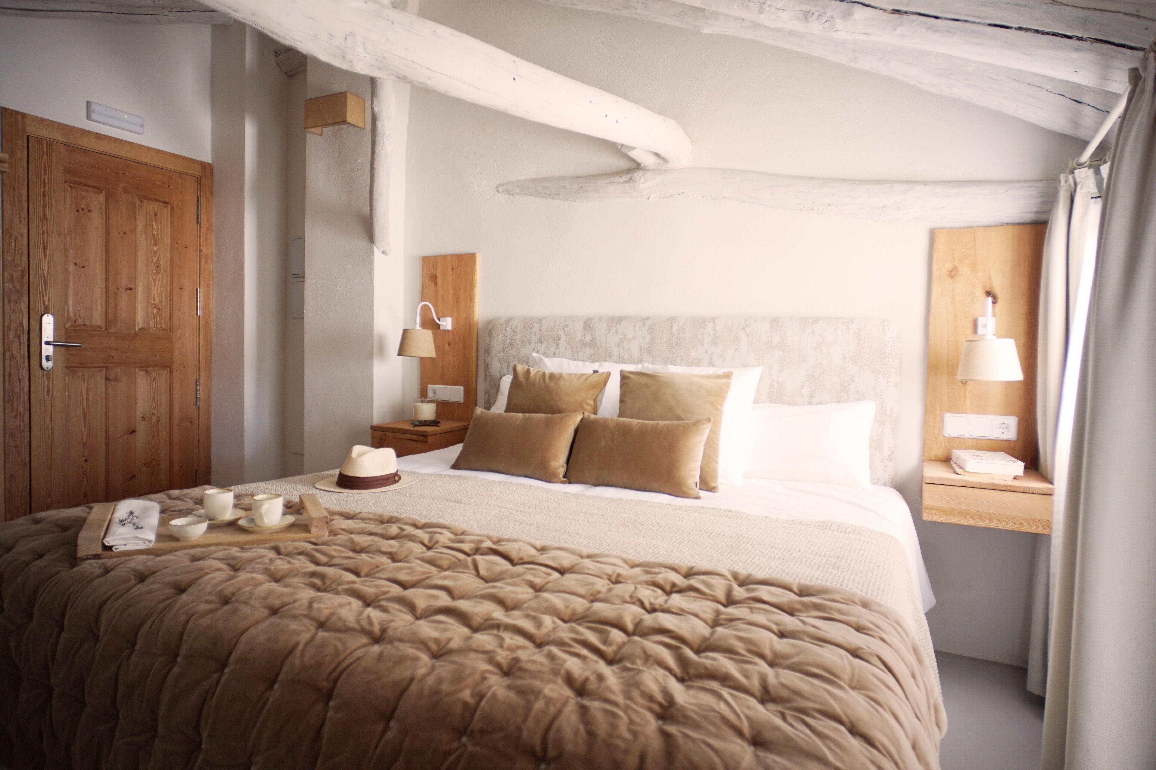 A bedroom with a large bed, wooden headboard, bedside tables with lamps, and a wooden wardrobe.