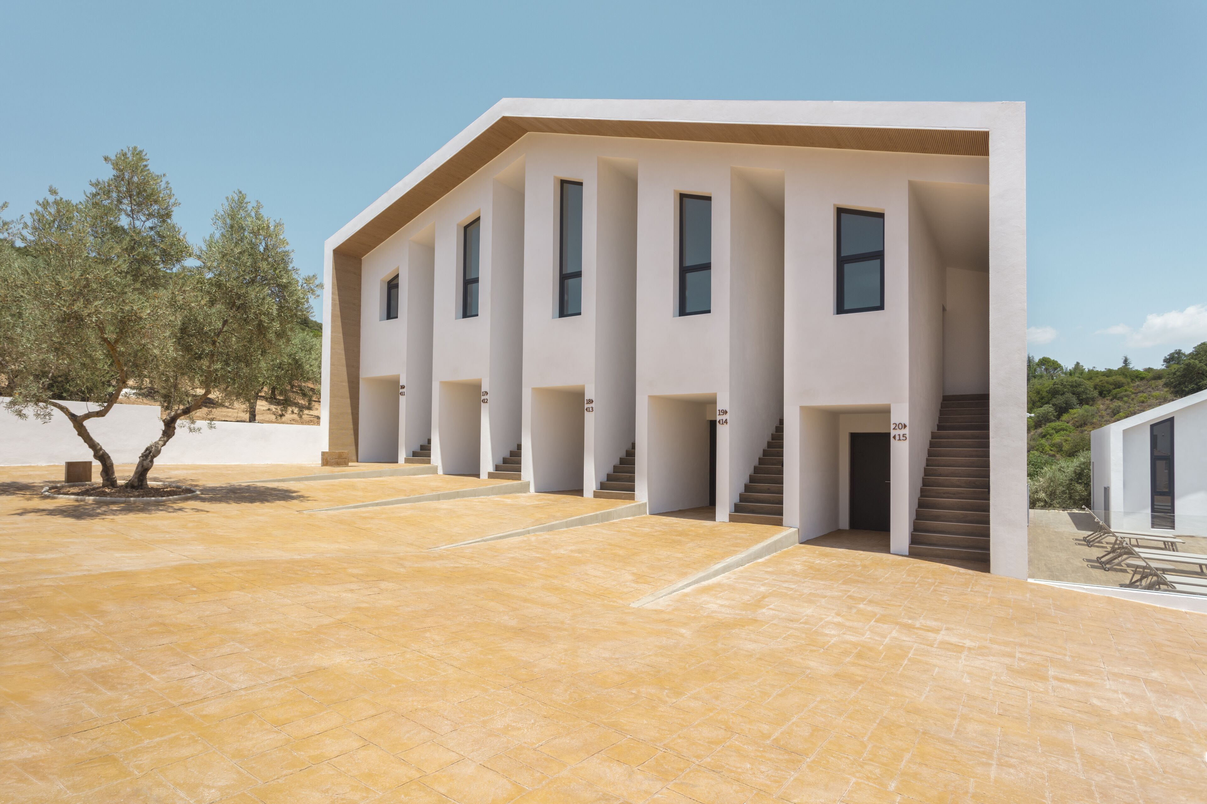 A modern building with a flat roof, multiple windows, and a tiled courtyard.