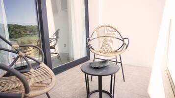 Un balcon agrémenté de fauteuils en osier et d’une petite table, offrant une vue sur un paysage pittoresque.