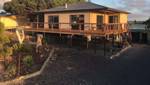 Una casa a due piani con una veranda in legno, ampie finestre e un camino.