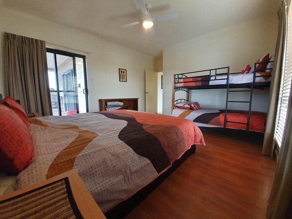 A room with a large bed, a bunk bed, a ceiling fan, and a window with curtains. - Chill n sea - Beautiful elevated holiday home (Marion Bay)