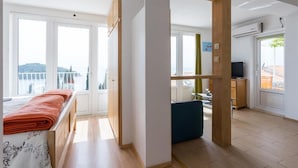 A room with a bed, a desk, a chair, and a view of the outside.