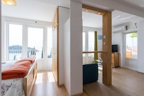 A room with a bed, a desk, a chair, and a view of the outside. - Charming Studio Apartment With Beautiful Panoramic sea View (Dubrovnik)