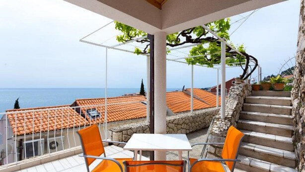 A terrace with a table and chairs, a stone staircase, and a view of the sea.
