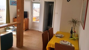 A dining area with a yellow tablecloth, chairs, and a small plant.