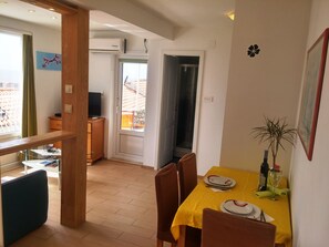 A dining area with a yellow tablecloth, chairs, and a small plant. - Charming Studio Apartment With Beautiful Panoramic sea View (Dubrovnik)