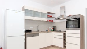 Una cocina moderna con armarios blancos, horno empotrado y lavavajillas.