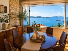 Un comedor con vista al mar, una pared de piedra y un reloj.