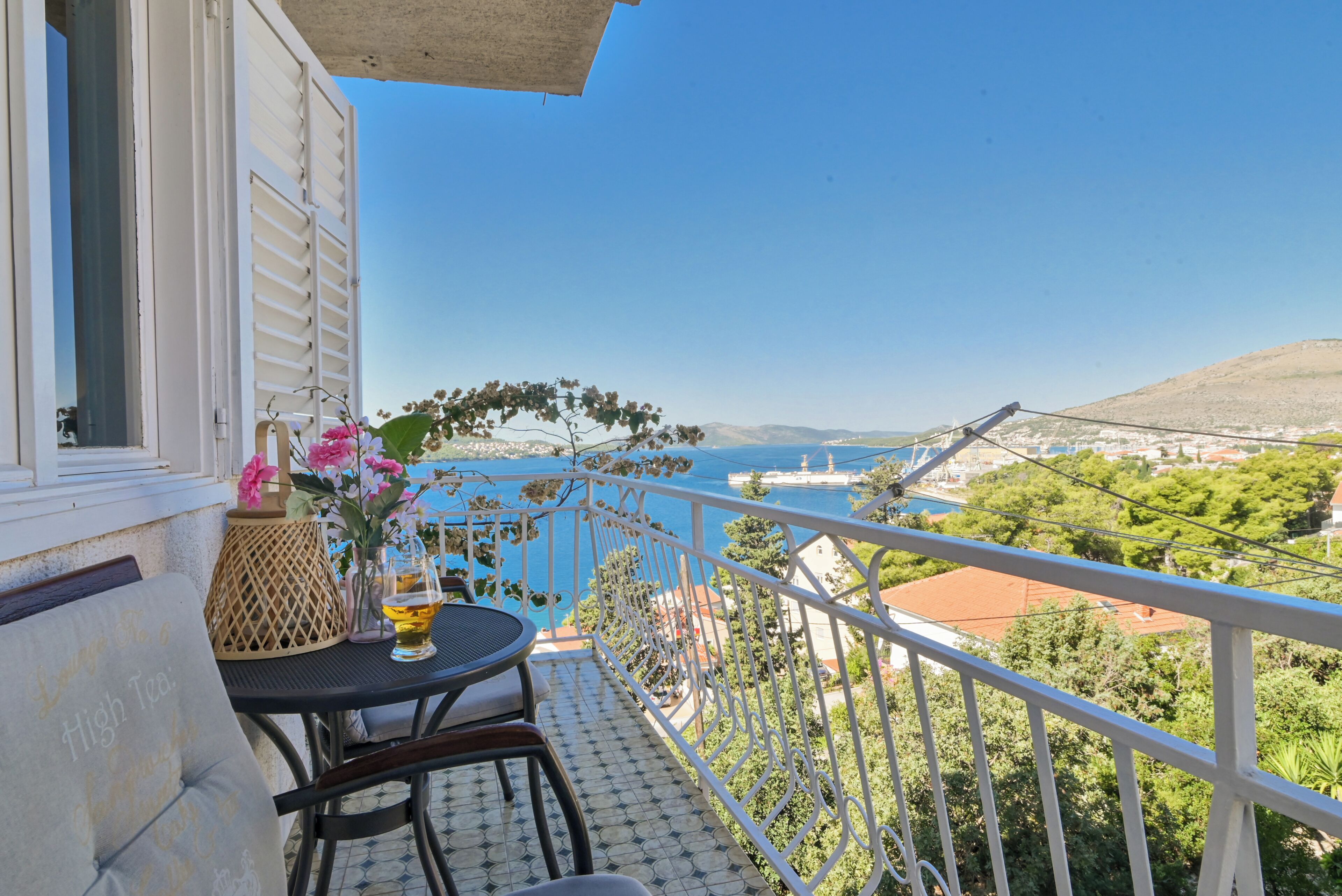 Ein Balkon mit Tisch und Stühlen, der einen schönen Blick auf das Meer und die Hügel bietet.