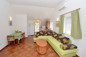 Ein Wohnzimmer mit einem grünen Sofa, einem Holztisch und einem Essbereich mit Tisch und Stühlen.