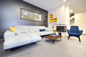 A modern living room with a white sectional sofa, a blue armchair, a wooden coffee table, and a large mirror on the wall.