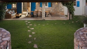 A stone building with blue shutters, a covered patio, and a grassy lawn. - Villa Flavia - Stunning Villa in Istria, Croatia (Umag)