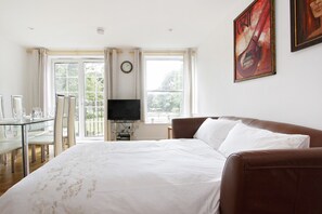 A hotel room with a bed, a TV, a dining table with chairs, and a window with curtains. - Westminster, London Eye, Big Ben 10 Minutes Walking (London)