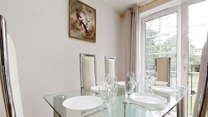 Een moderne badkamer met een glazen wastafelmeubel, twee spiegels en een groot raam met gordijnen.