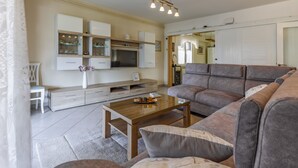 A modern living room with a grey sofa, a wooden coffee table, and a kitchen area with cabinets and a microwave. - Spacious and Comfortable Apartment in Medulin, Croatia (Medulin)