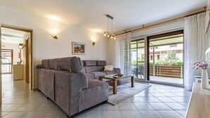 A modern living room with a grey sofa, a wooden coffee table, and a large sliding glass door leading to an outdoor balcony. - Spacious and Comfortable Apartment in Medulin, Croatia (Medulin)