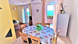 A dining area with a round table covered in a floral tablecloth, wooden chairs, and a small green plant on the table. - Holiday Apartment With a Balcony and sea View, Just 300 Metres From the Beach (Bol)