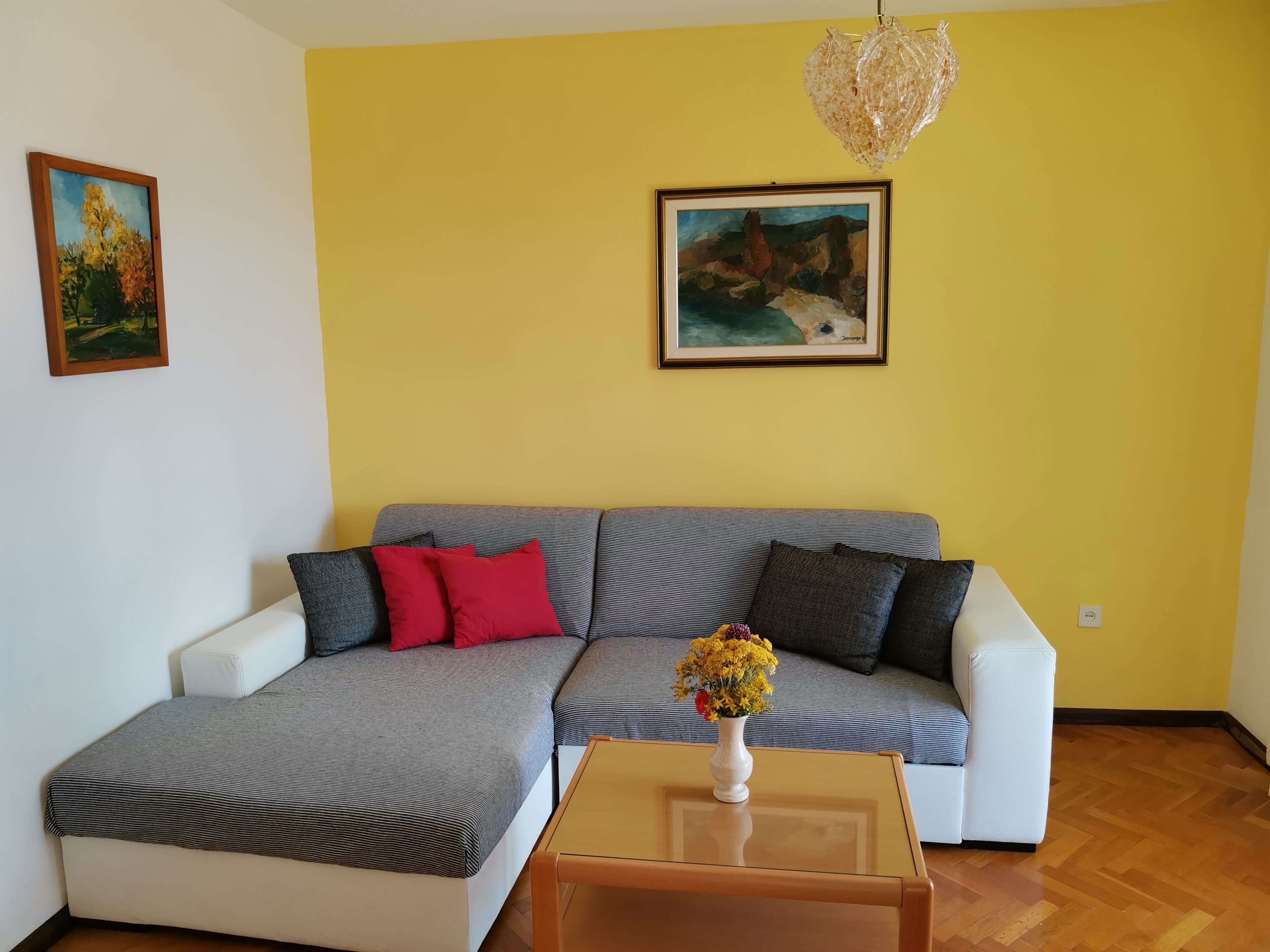 A living room with a sofa, a coffee table, and two paintings on the wall.