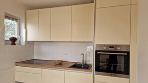 A compact kitchen with white cabinets, a built-in oven, and a small window. - Holiday Apartment With a Balcony and sea View, Just 300 Metres From the Beach (Bol)