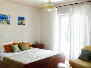 A bedroom with a bed, a nightstand, a lamp, and a chair.