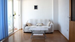 Ein Wohnzimmer mit einer Couch, einem Glastisch und einem Bild an der Wand.