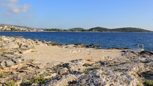 Eine felsige Küstenlinie mit freiem Blick auf das Meer und sanfte Hügel in der Ferne.