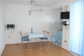 A dining area with a table, chairs, a TV, and a microwave. - Apartments 4 Dolphins Rogoznica (Rogoznica)
