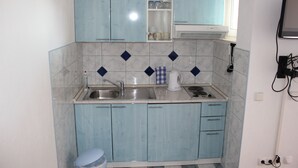 Eine kleine Küche mit hellblauen Schränken, einem Spülbecken und einer Kaffeemaschine.