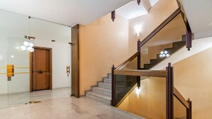Een modern interieur met een glazen deur, een houten deur en een trap met een glazen balustrade.