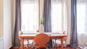 Een eethoek met een houten tafel, vier stoelen en een vaas met een plant.