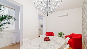 Un comedor moderno con una mesa de mármol, sillas rojas y una araña.