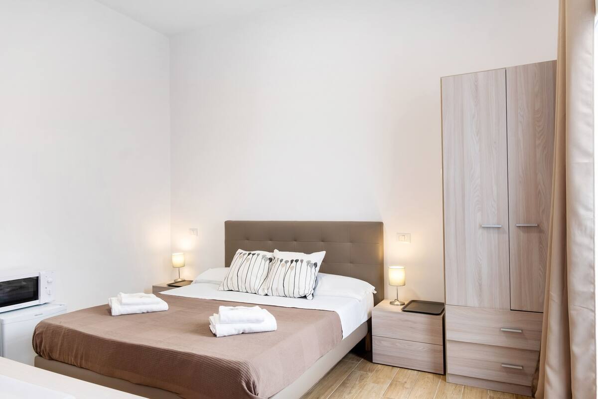 Een hotelkamer met een bed, nachtkastjes, een kledingkast en een magnetron.