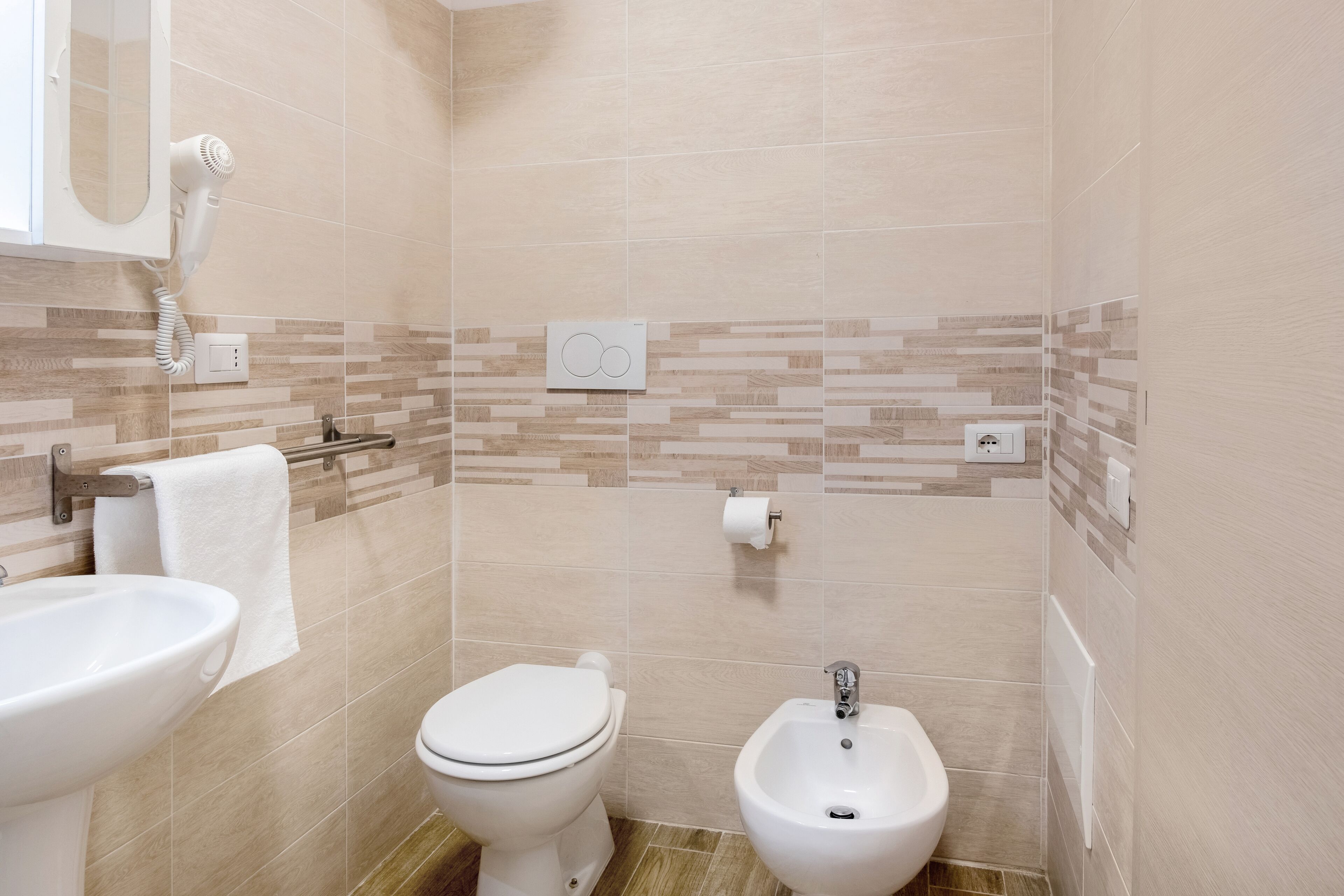 A bathroom with a toilet, bidet, and sink.