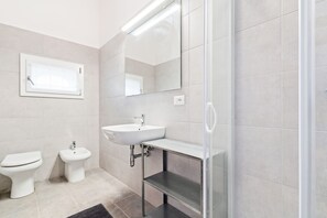 A modern bathroom with a toilet, bidet, sink, and a glass shower enclosure. - Ponte di Rialto Penthouse with Panoramic Terrace (Venice)