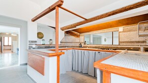 Une cuisine avec un plafond orné de poutres en bois, un dosseret carrelé et un grand miroir au-dessus du plan de travail.