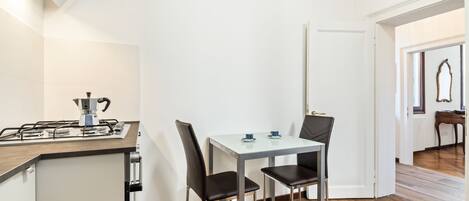 Una cocina compacta con estufa a gas, dos sillas y una mesa pequeña.