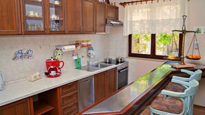 Una cocina con armarios de madera, un lavamanos de acero inoxidable, una máquina de café y una zona de bar con taburetes.