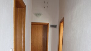 Un couloir avec des portes en bois et un sol carrelé.