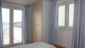 Une chambre à coucher avec un lit, une armoire et une fenêtre avec des rideaux.