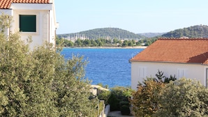 A coastal building with a red-tiled roof, a view of the sea, and surrounding greenery. - Welcome to Apartments 4 Dolphins, Rogoznica, Croatia (Rogoznica)