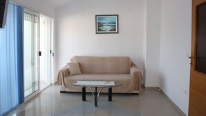 Ein Wohnzimmer mit einem beigefarbenen Sofa, einem Glastisch und einem gerahmten Bild an der Wand.